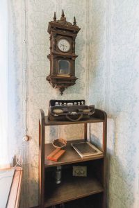 Часы в резном футляре — подарок "Великому певцу земли русской от Общества вспомоществования учащимся женщинам в Москве", которому Шаляпин оказывал материальную поддержку. На этажерке — дорожные принадлежности артиста